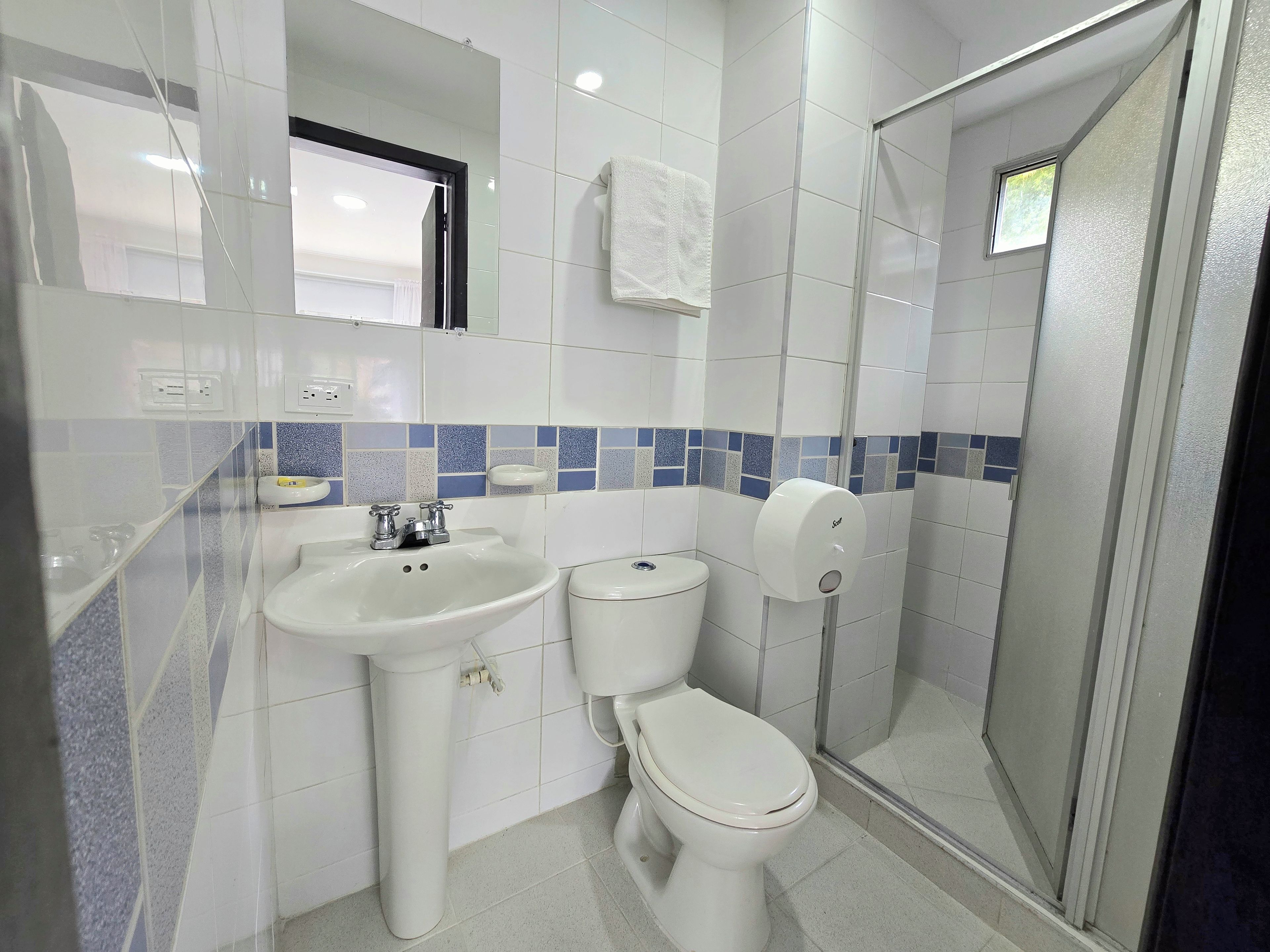 Un baño con lavamanos, inodoro y cabina de ducha de vidrio.