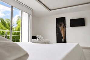 A modern hotel room with a large window, a neatly made bed, and a wall-mounted TV.