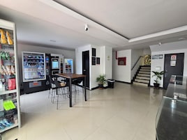 A clean lobby with vending machines, a table with chairs, a trash bin, and a staircase.