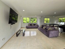Una sala de estar moderna con una televisión de pantalla plana, dos sofás, una mesa de centro y una mesa de ping pong.