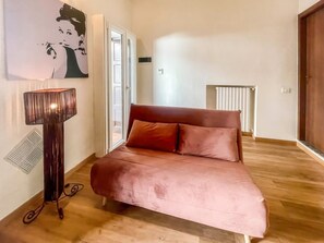 A room with a bed, a radiator, a wall-mounted picture, and a floor lamp.
