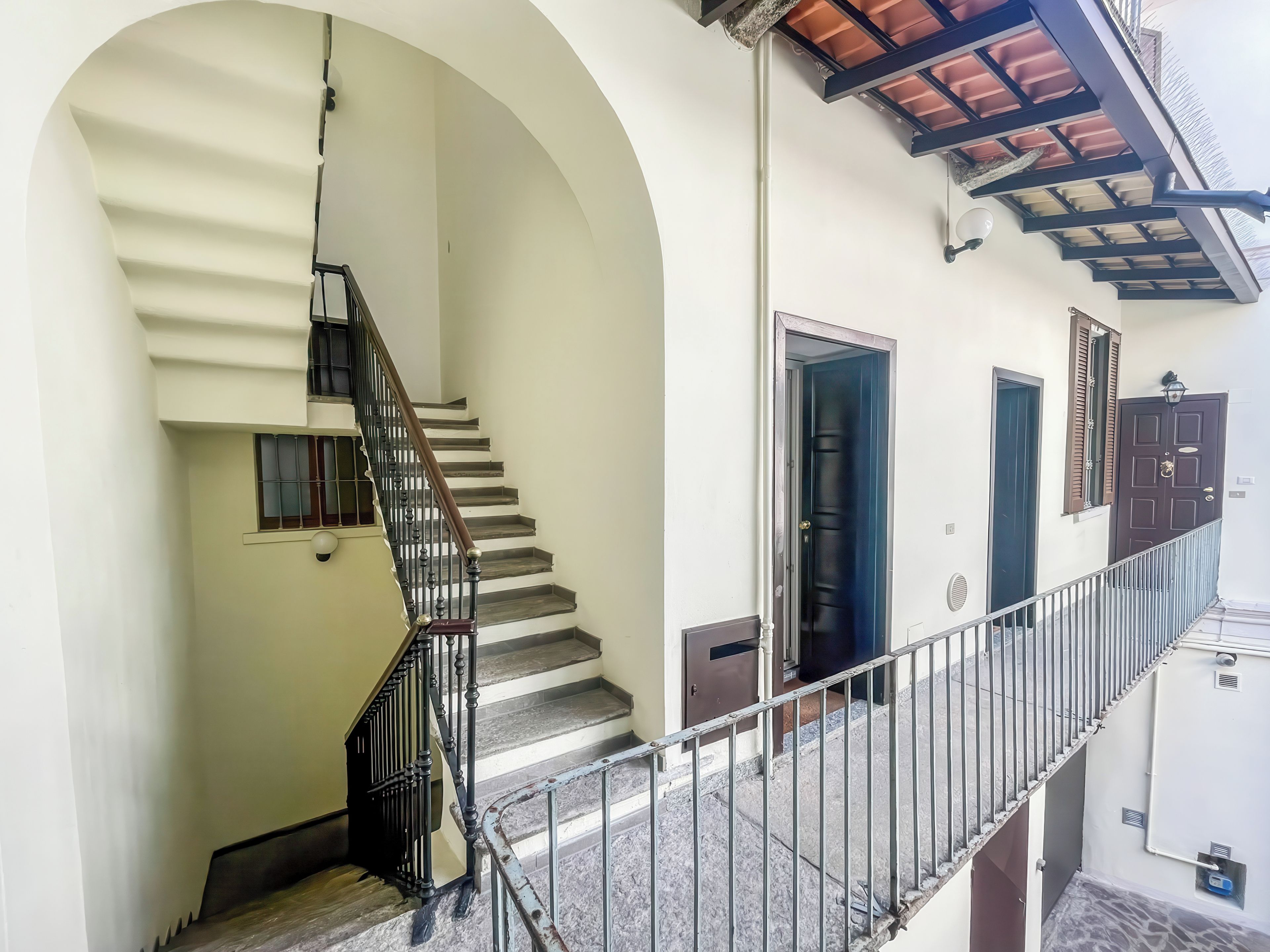 A staircase with a metal railing, a door, and a window with shutters.