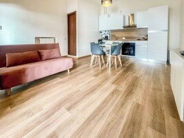 Un espacio habitable moderno con sofá, mesa de comedor, sillas y zona de cocina.