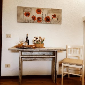 A rustic wooden table with a woven basket, a bottle, and a vase of flowers.
