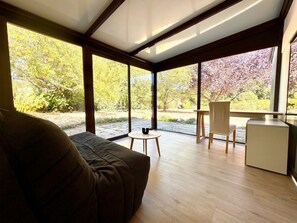 Un interior moderno con ventanas amplias, un sofá, una mesita y una silla.