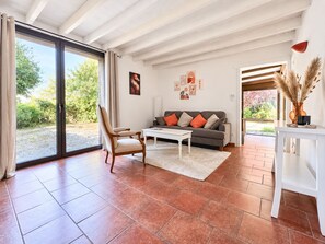 A living room with a sofa, armchair, coffee table, and a view through a glass door to an outdoor area. - La Parenthèse Suryssoise: Sit down, take a breath... Near Sancerre and the Loire River (Sury-ès-Bois)