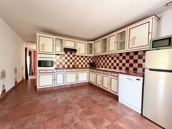 Una cocina con armarios blancos, un salpicadero escocés rojo y blanco y un lavavajillas blanco.