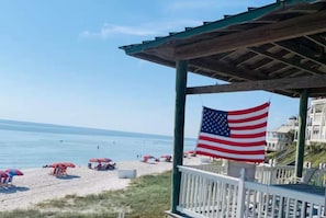 A beach scene with a wooden pavilion, an American flag, and beach umbrellas. - NEW Seaglass Villa | Golf Cart + 5 Bikes | 30A (Santa Rosa Beach)