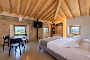 Ein Schlafzimmer mit einem großen Bett, einem Tisch mit Stühlen, einem Fernseher und einer Steinwand.