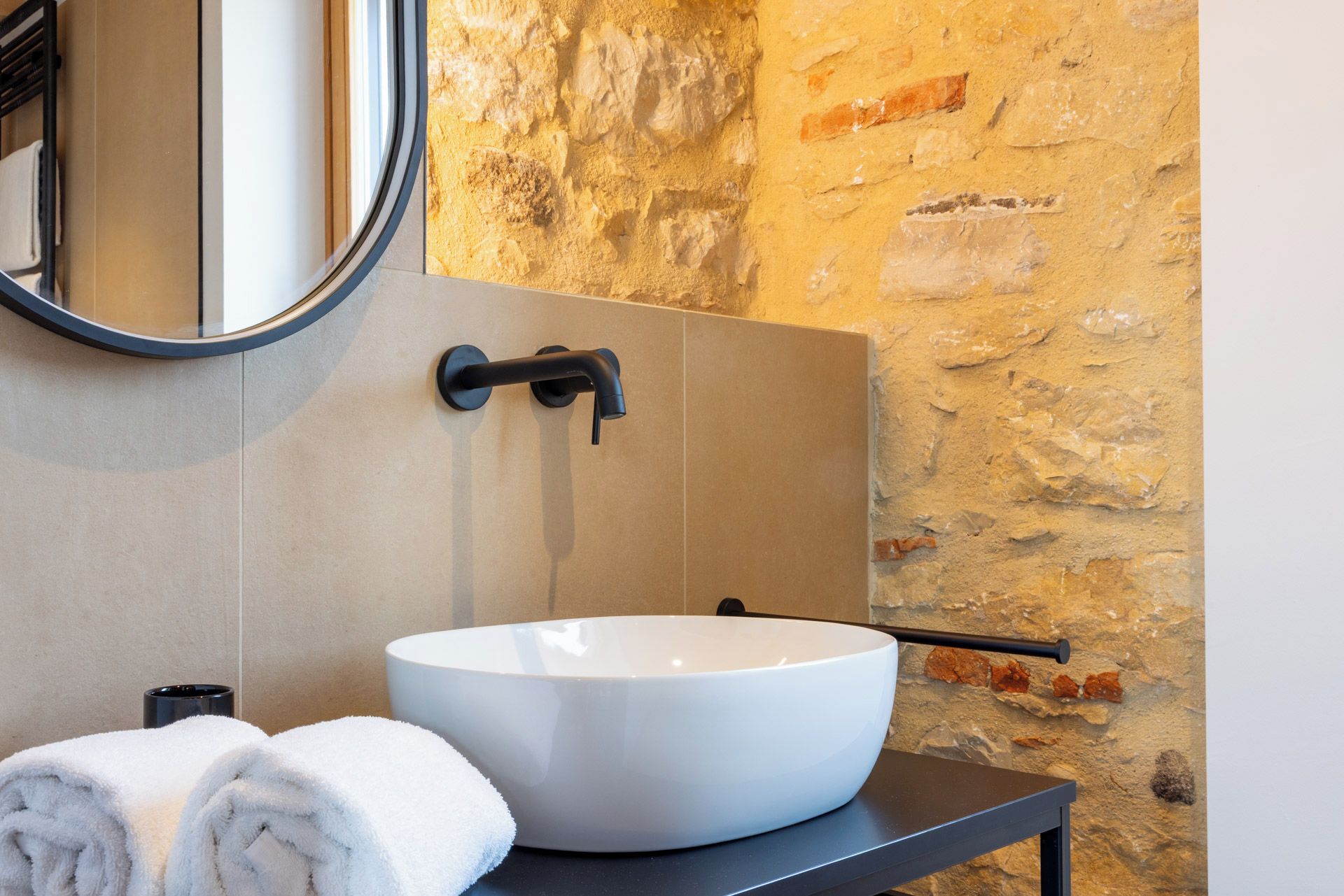 Ein Badezimmer mit einem weißen Waschbecken, einem Handtuch und einem Spiegel.
