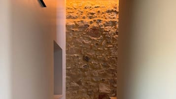 A staircase with a stone wall background and a wooden ceiling.