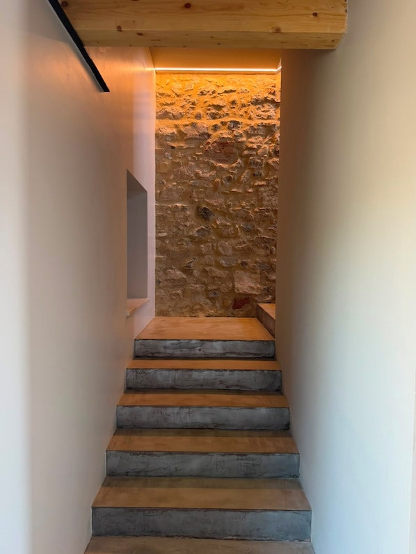 A staircase with a stone wall background and a wooden ceiling.