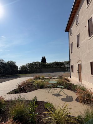 A building with a courtyard, outdoor seating, and a view of trees and a fence.