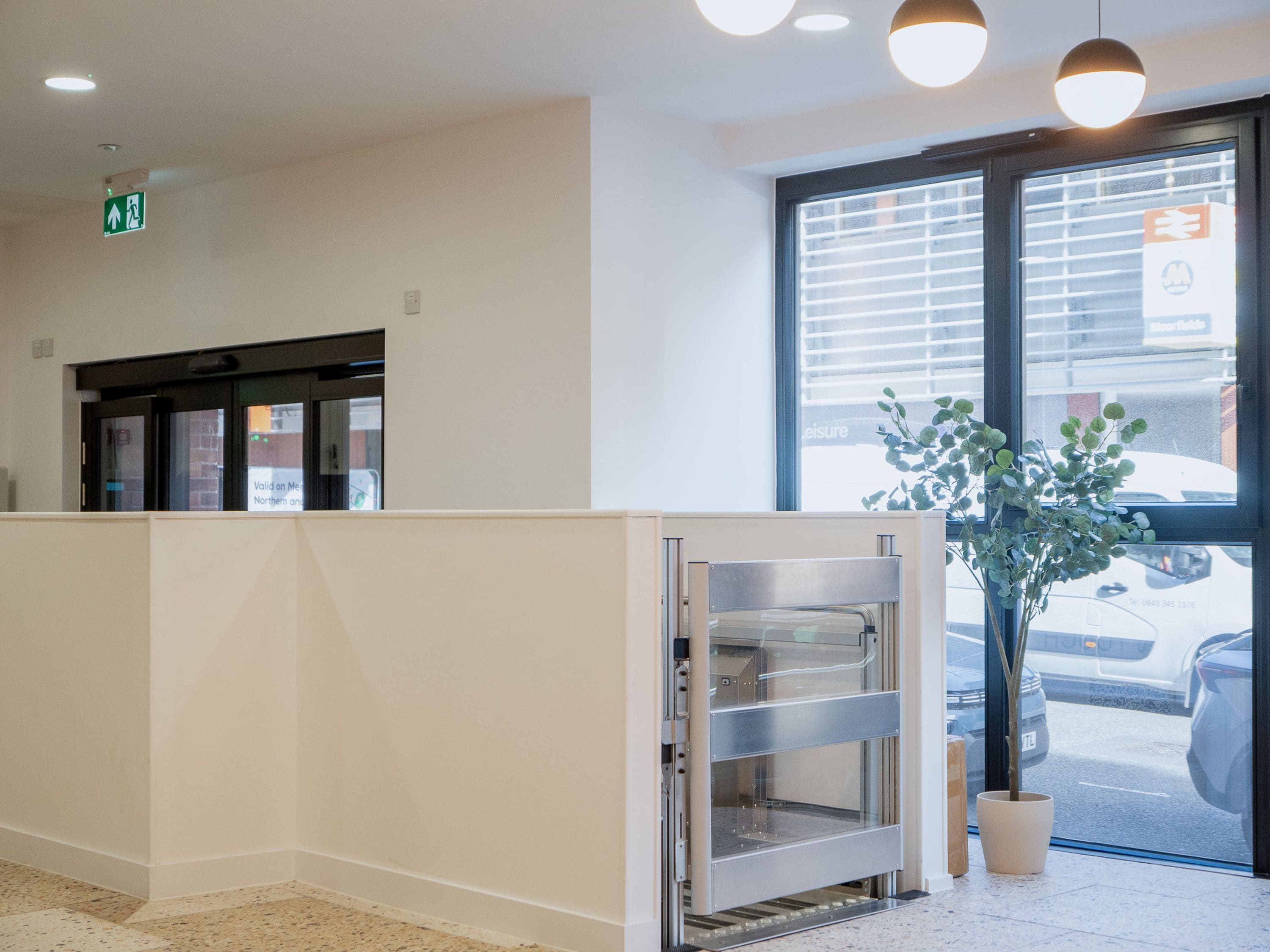 A clean, modern interior with a reception desk, a potted plant, and a view of the street outside.