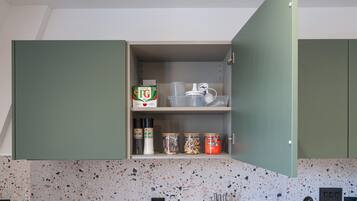 Eine Küche mit gefleckter Spritzschutzwand, einer Arbeitsplatte mit Geschirr und einem Schrank mit Aufbewahrungsmöglichkeiten.