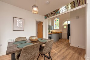 Uma área de refeições com mesa de madeira, cadeiras e luminária pendente.