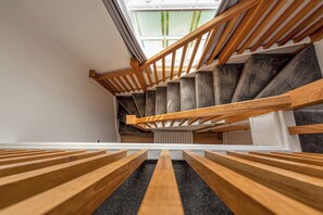 Una escalera de madera con tragaluz arriba, que baja a un nivel inferior.