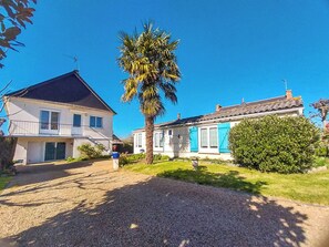 A residential area with two houses, one with a balcony and the other with blue shutters, surrounded by greenery and a clear sky. - Vrbo Property (Beaussais-sur-Mer)