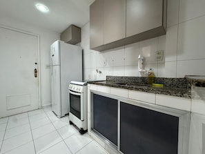 A kitchen with white cabinets, a built-in oven, a refrigerator, and a granite countertop. - 3min da Praia de Copacabana (Rio de Janeiro)