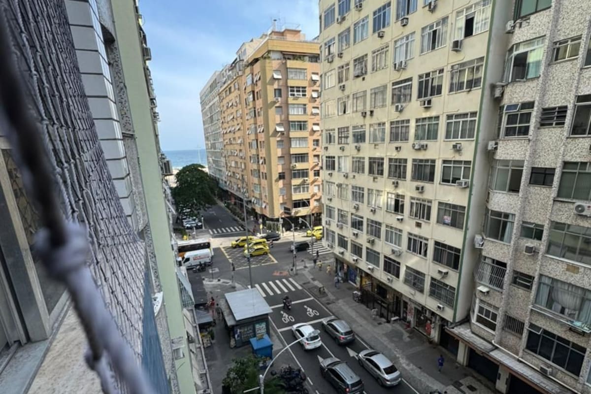 A city street with multi-story buildings, vehicles, and a pedestrian crossing.