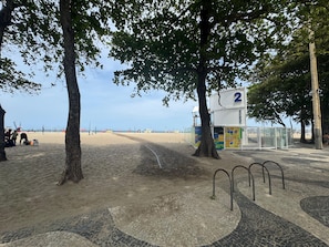 A beach area with trees, a covered seating area, and a tiled walkway. - 3min da Praia de Copacabana (Rio de Janeiro)