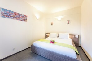 Ein Hotelzimmer mit einem Bett, einem Bild an der Wand und zwei kleinen gerahmten Bildern.