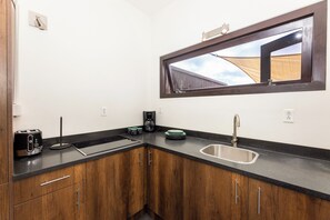 Eine kompakte Küche mit eingebautem Herd, einer Spüle und einem Fenster über der Arbeitsplatte.