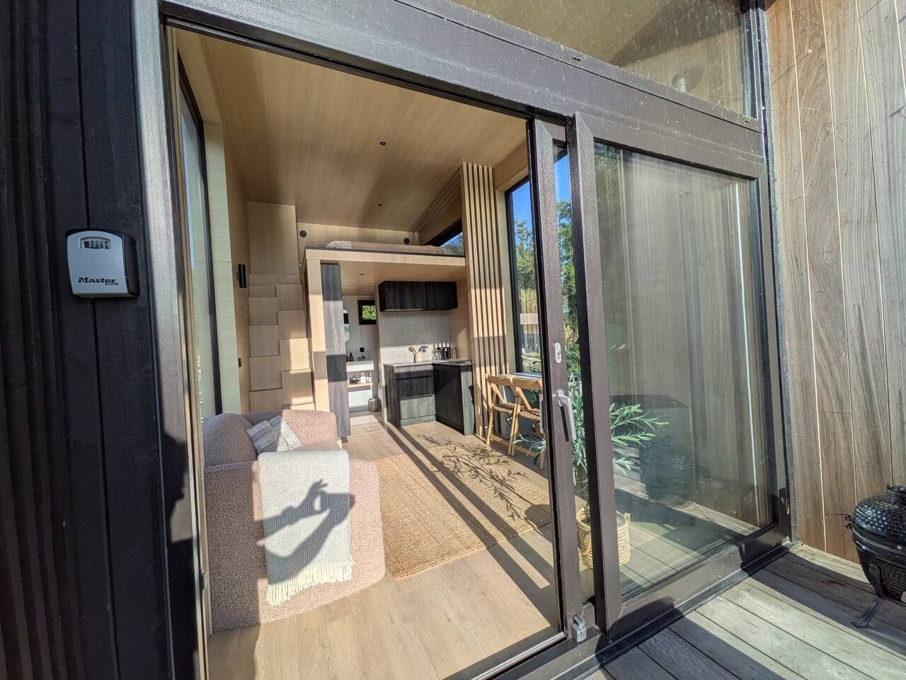 Een modern interieur met een keuken, een eetgedeelte en een glazen schuifdeur die leidt naar een buitenruimte.