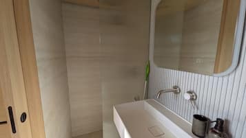 Een moderne badkamer met een houten deur, een witte wastafel, een spiegel en een douchehoek.