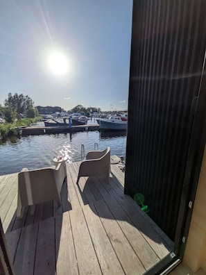A wooden deck with two chairs and a small table, overlooking a marina with boats. - Surla Suite Poliente (Amsterdam)