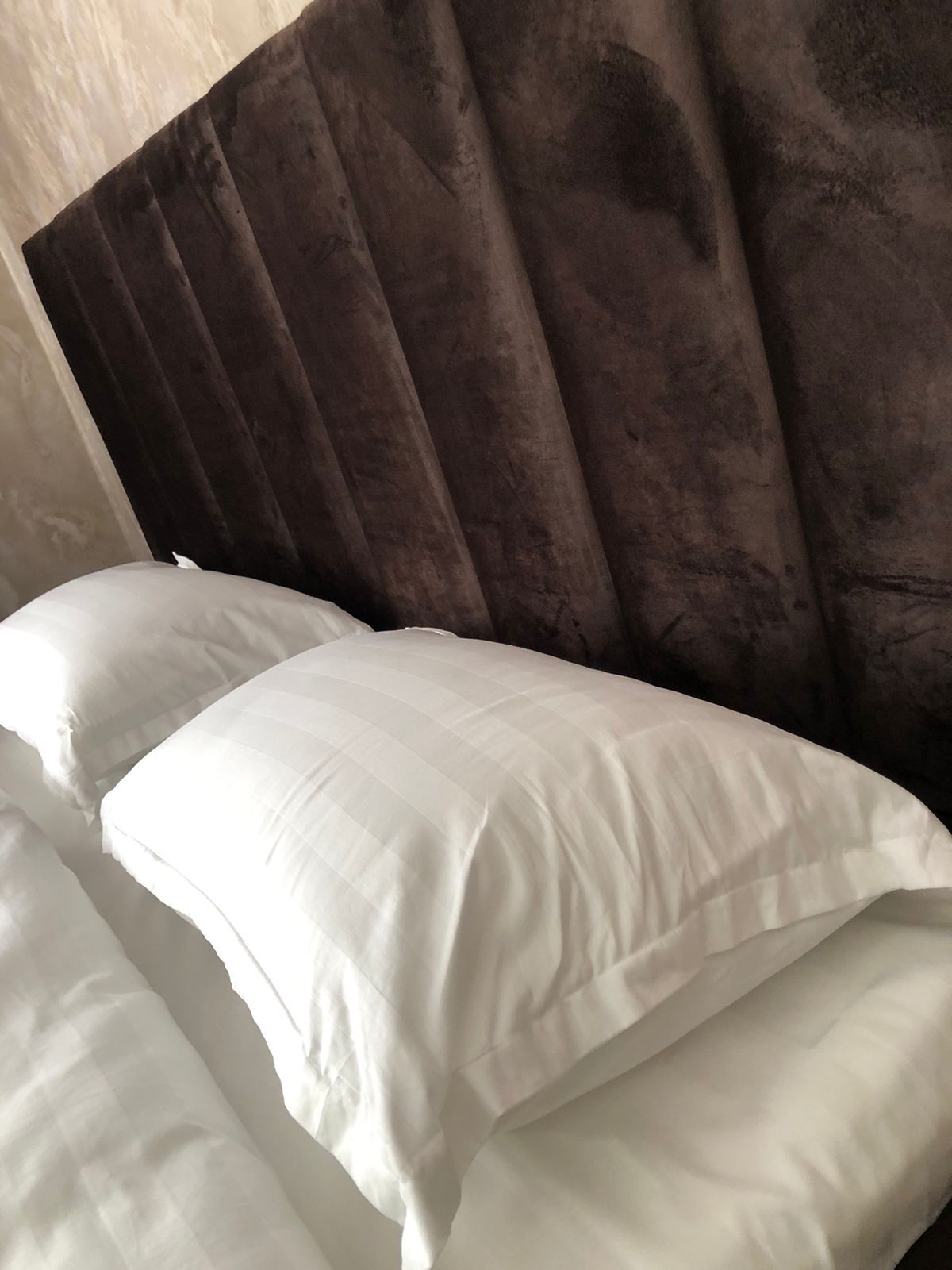 A bed with white pillows and a dark headboard.