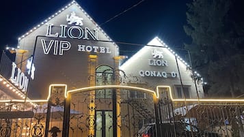 Das Äußere des Lion VIP Hotels mit beleuchteter Beschilderung und einem schmiedeeisernen Tor.