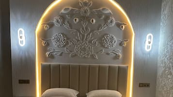 Un dormitorio con una cama grande, un cabecero decorativo, mesitas de noche y una pared con líneas verticales.