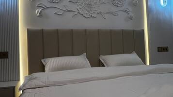 A hotel room with a bed, pillows, and a decorative floral headboard.