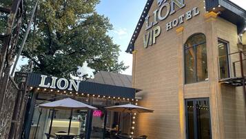 The exterior of the Lion Hotel with a brick facade, large windows, and outdoor seating area with umbrellas.