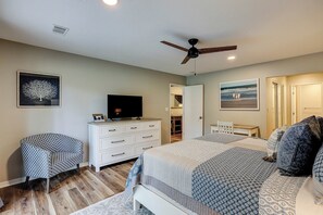Ein Schlafzimmer mit einem Bett, einem Schminktisch, einem Fernseher und einem Deckenventilator.