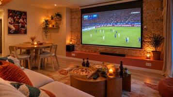 Un salon confortable avec un grand téléviseur à écran plat, des meubles en bois et une boîte à pizza.