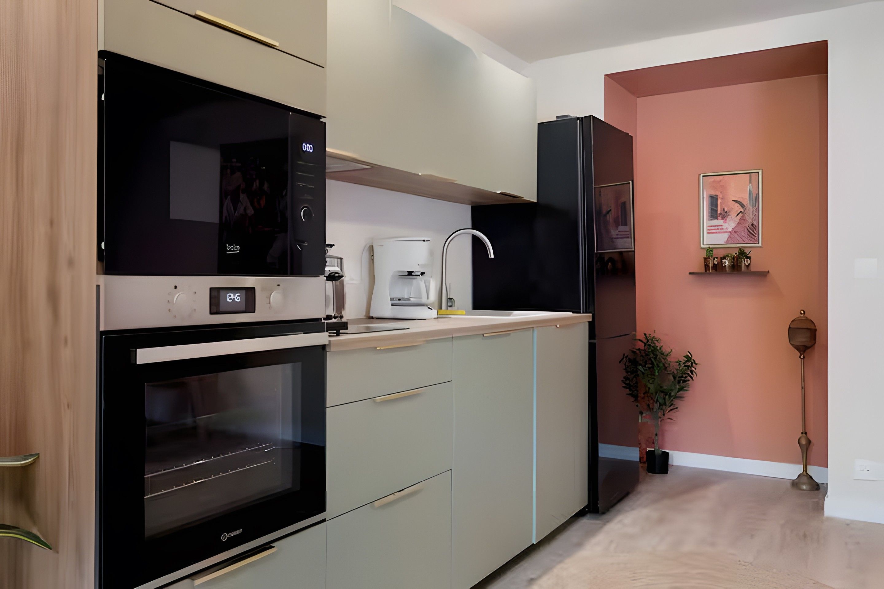 A modern kitchen with a built-in oven, a coffee machine, and a refrigerator.