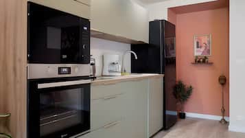A modern kitchen with a built-in oven, a coffee machine, and a refrigerator.