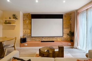 Un salon avec un mur en pierre, un téléviseur à écran plat fixé au mur, une table basse en bois et un canapé.