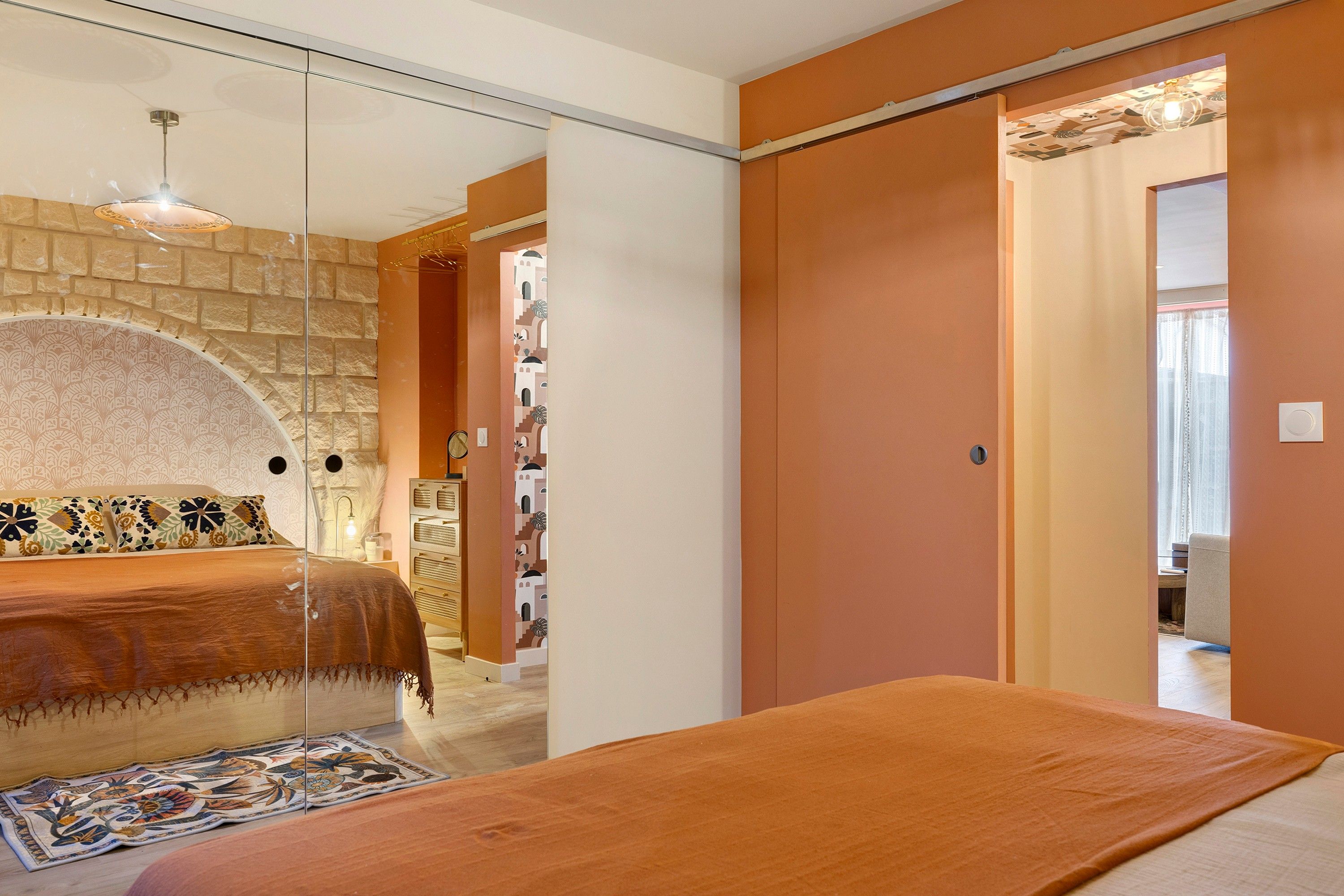Une chambre à coucher avec un lit, un miroir, une armoire et un tapis à motifs.