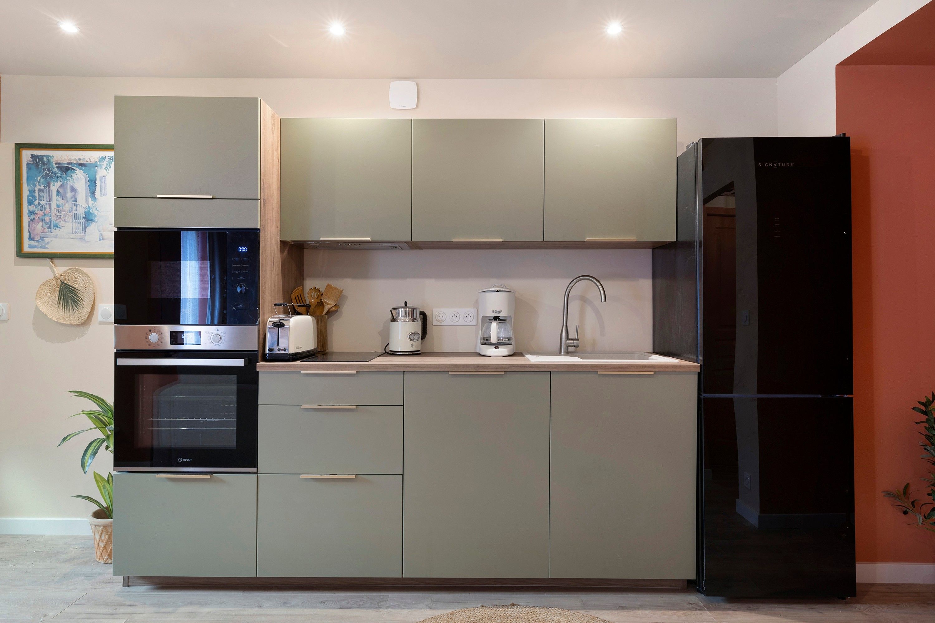 Een moderne keuken met inbouwapparatuur, een spoelbak en een koelkast.