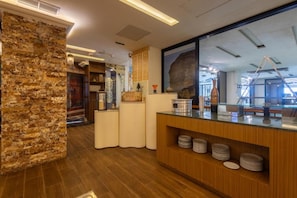 Una zona de recepción con pared de piedra, mostrador de madera y un ventanal grande.
