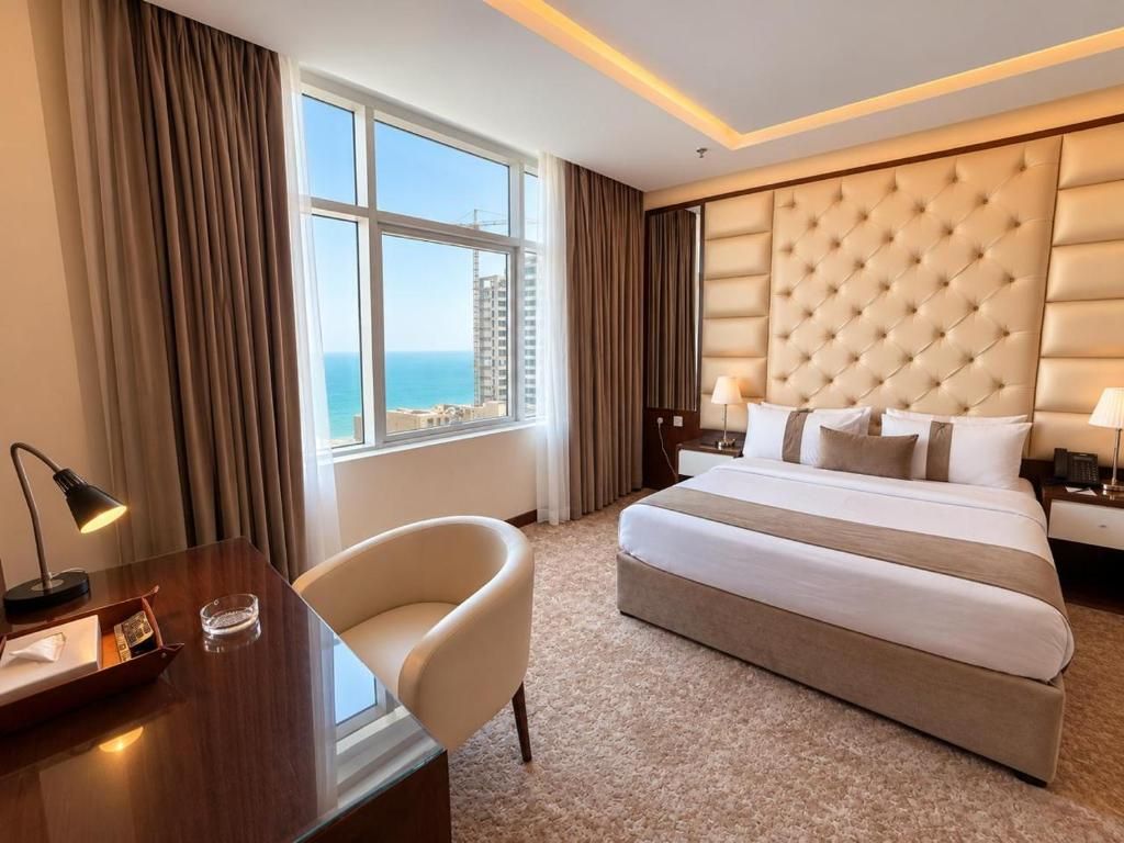 Habitación de hotel con una cama grande, un escritorio con lámpara, una silla y vistas al mar.