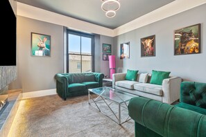 A modern living room with green and white sofas, a glass coffee table, and artwork on the walls. - 3 Bedford House - Close to Town and Seafront (Tenby)