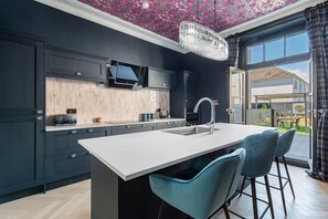 Une cuisine moderne avec des meubles de couleur sombre, un grand îlot central et un téléviseur encastré.