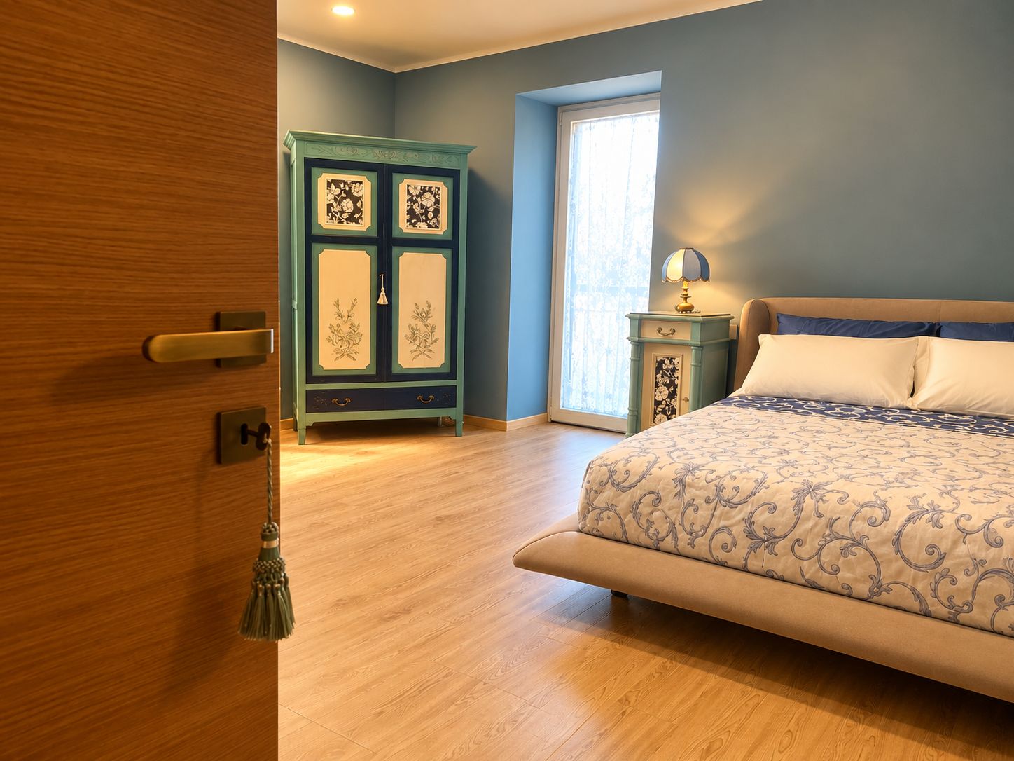 A bedroom with a bed, a wardrobe, a nightstand, and a window.