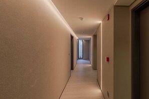 A hallway with a light wood floor, beige walls, and a door at the end. - MOT Rentals + Design SohoHaus '108' - 3 pax Full Amenities (Buenos Aires)