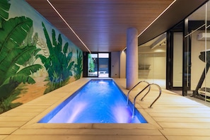 A swimming pool with a wooden deck, surrounded by a mural of tropical plants. - MOT Rentals + Design SohoHaus '305' - 3 pax Full Amenities (Buenos Aires)
