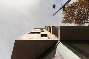 A modern building with a geometric facade, a streetlight, and a tree with autumn leaves. - MOT Rentals + Design SohoHaus '305' - 3 pax Full Amenities (Buenos Aires)